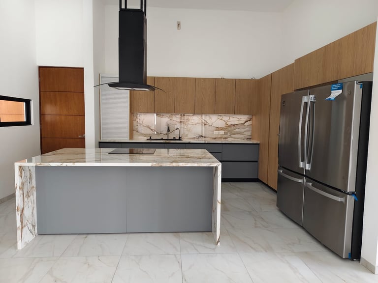 Modern kitchen with gray island, stainless steel appliances, wood paneling, and marble flooring