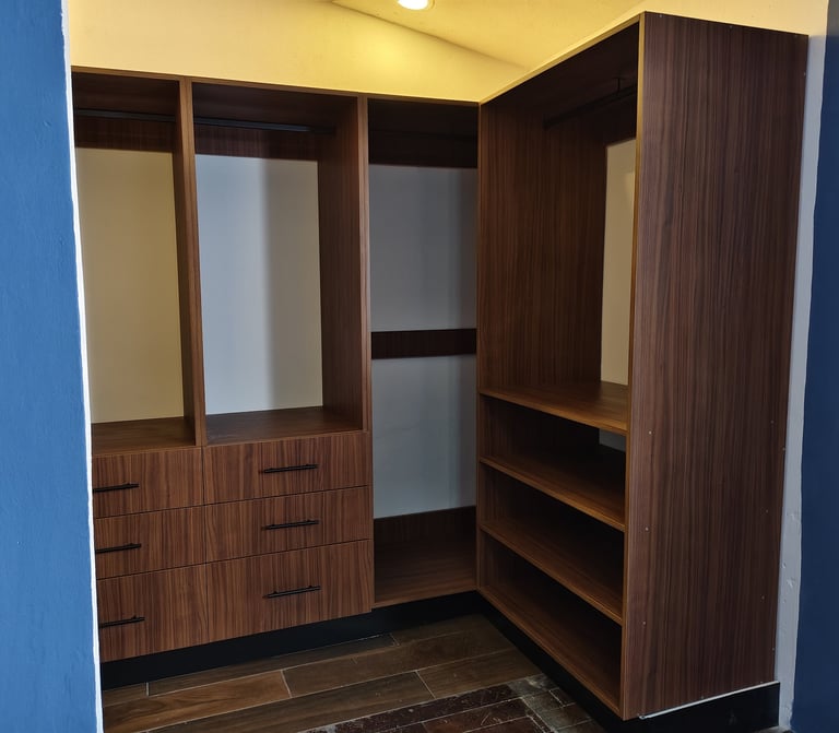 Modern walk-in closet with dark wood cabinetry, shelving, and drawers against blue walls with yellow ceiling