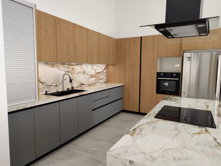 Modern kitchen with dark gray cabinets, natural wood paneling, marble countertops, stainless steel appliances, and island with cooktop