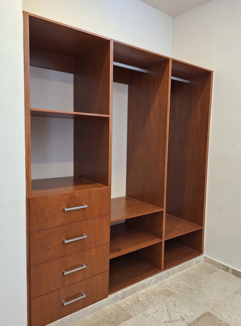 Custom wooden closet system with dark brown cabinets, shelving, hanging rods, and drawers built into white wall