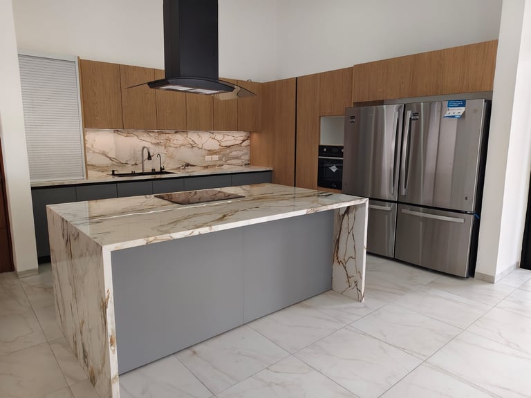 Modern kitchen with marble island, wood cabinets, stainless steel appliances, and black range hood