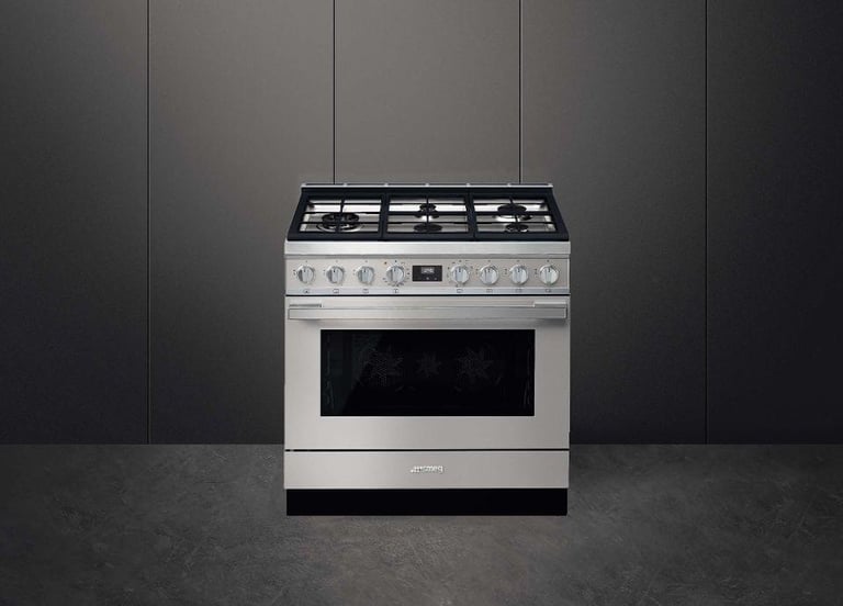Stainless steel dual-fuel range against gray tiled wall